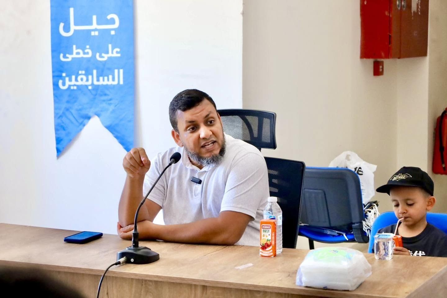 محاضر يتحدث إلى الحضور وبجانبه طفل في نشاط لإحياء